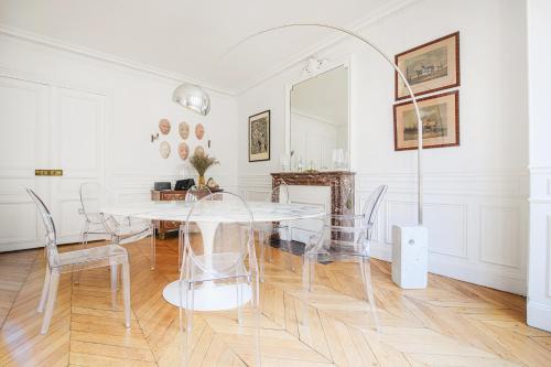 une salle à manger blanche avec une table et des chaises blanches dans l'établissement Appartement d'une chambre près de Montmartre, à Paris