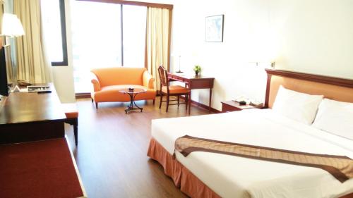 a hotel room with a bed and a chair at Tai Pan Hotel in Bangkok