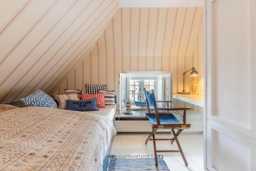 a bedroom with a bed and a chair next to a window at Das-Kommandeur-Haus-Ihr-Familien-Ferienhaus-in-Nieblum-auf-Foehr in Nieblum