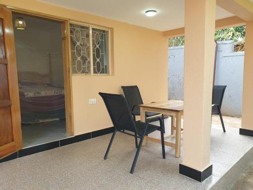 a dining room with a table and black chairs at Alison & Dave's Guesthouse in Entebbe