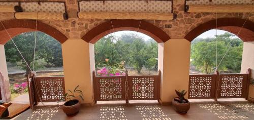 a room with three arched windows and potted plants at Haveli Anirudh - Royalty Redefined in Jaipur