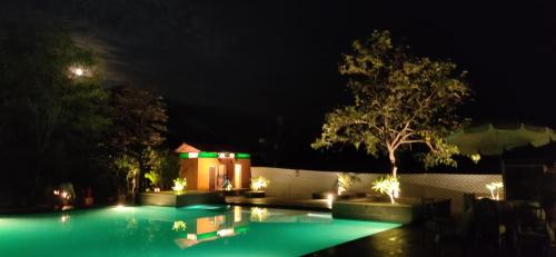 a swimming pool lit up at night with lights at Haveli Anirudh - Royalty Redefined in Jaipur