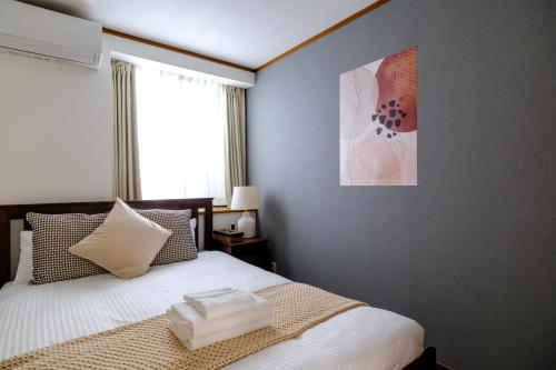 a bedroom with a bed with white sheets and a window at Kichijoji Urban Retreat - 2F Boutique House - Steps to Inokashira Park & Ghibli Museum アキサポステイ吉祥寺 in Kichijōji