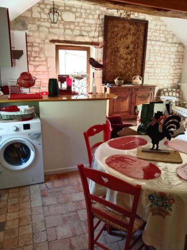 une cuisine avec une table et une machine à laver dans l'établissement LE COMPOSTELLE BATIMENT LA RENAISSANCE, à Courchamps