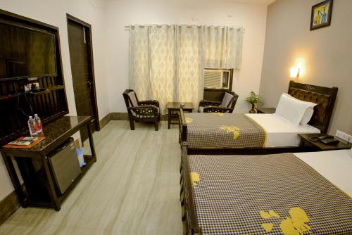 a hotel room with two beds and a table and chairs at Pearl of Taj Home Stay in Agra