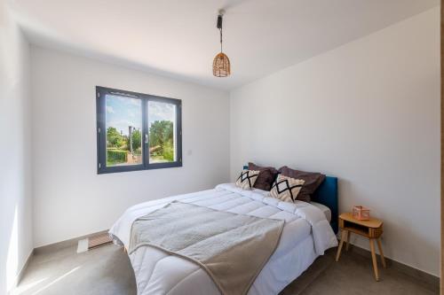 une chambre blanche avec un lit et une fenêtre dans l'établissement Les Lauriers Roses - Maison climatisée piscine, à Bessas
