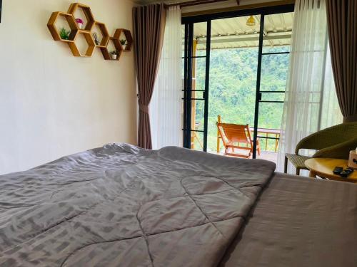 a bedroom with a bed and a large window at ม่านฟ้า โฮมสเตย์ MaanFah Homestay in Chiang Rai