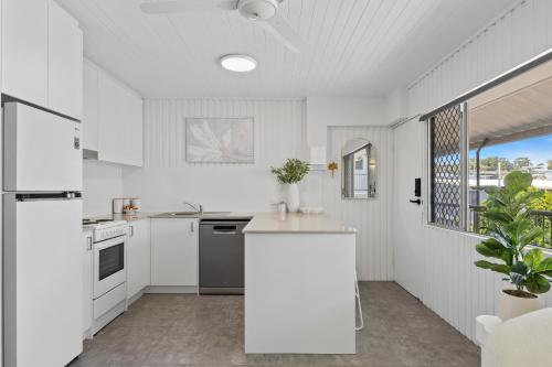 a kitchen with white appliances and a large window at Alex Beachside Pet Friendly 2 Bed Apartment in Alexandra Headland