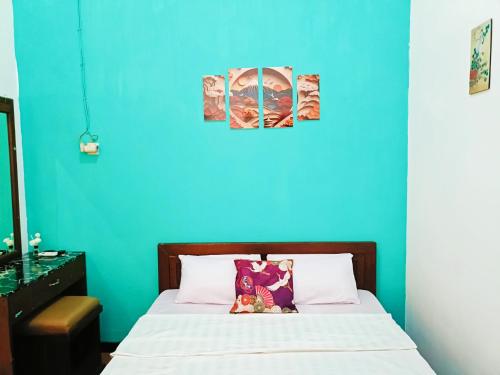 a bedroom with a blue wall and a bed at YUTAKA INN Stasiun Kota Madiun in Madiun