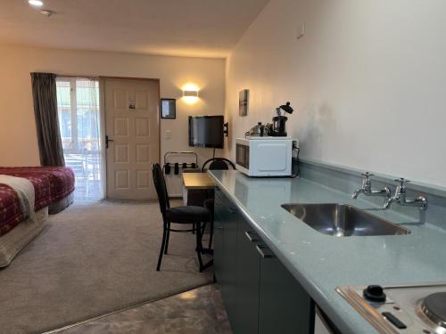 a kitchen with a sink and a room with a bed at ASURE Ambassador Motor Lodge in Oamaru