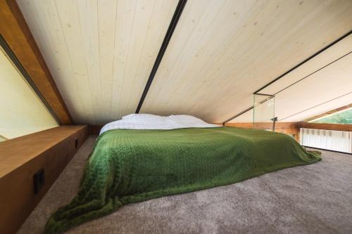 a bedroom with a green comforter on a bed at Lake view ODYL Holiday House with Sauna and Seasonal Hot-tub in Pindi