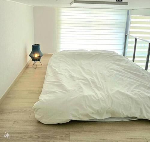 a bed with a white blanket and a lamp in a room at Majestic Seoul Stay Central in Seoul