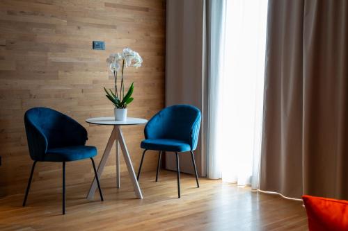 two blue chairs and a table with a vase of flowers at MòN Luxury Rooms SPA in Nicolosi