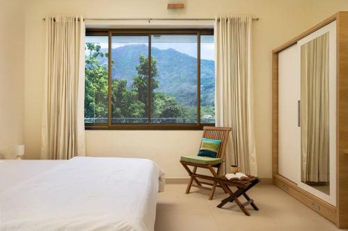 a bedroom with a bed and a chair and a window at 2 premium rooms with pool&by lake close to Vagamon in Muttam