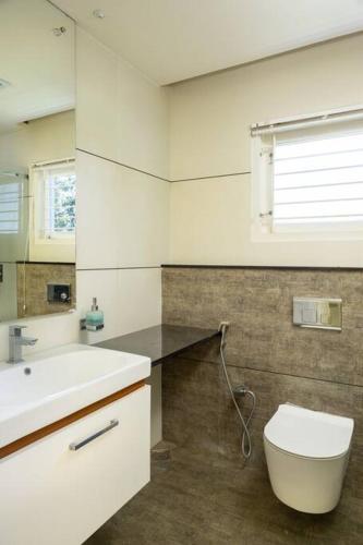 a bathroom with a white sink and a toilet at 2 premium rooms with pool&by lake close to Vagamon in Muttam