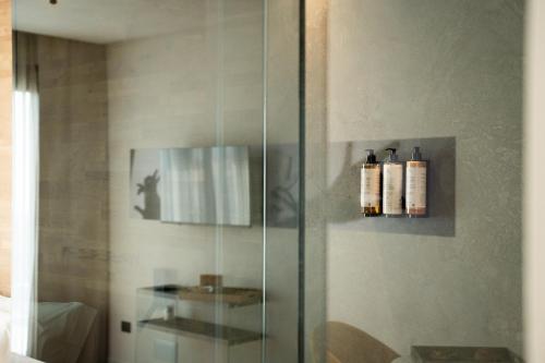 a glass shower stall with two bottles on the wall at MòN Luxury Rooms SPA in Nicolosi