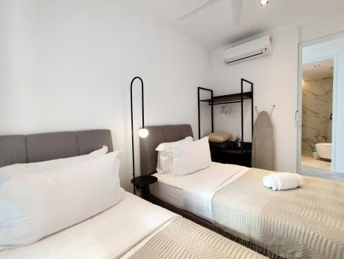 a white bedroom with two beds and a mirror at Lumi Tropicana in Petaling Jaya