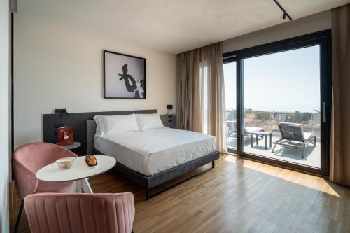 a bedroom with a bed and a table and a balcony at MòN Luxury Rooms SPA in Nicolosi