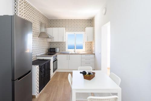 a kitchen with white cabinets and a white table and chairs at Casa Camila - Charming retreat & terrace, Hierro in Taibique