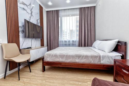 ein Hotelzimmer mit einem Bett und einem Fernseher in der Unterkunft Business Class Residential complex EXPO Boulevard in Astana