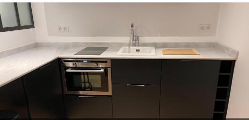 une cuisine avec un évier et une cuisinière dans l'établissement Joli studio au cœur de Paris, à Paris