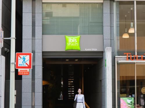 a woman walking in front of a ups store at ibis Styles Kyoto Shijo in Kyoto