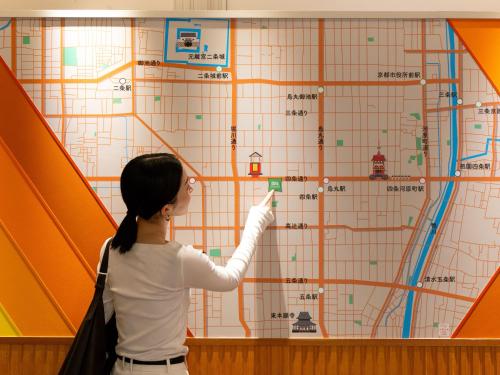 a woman pointing to a map on a wall at ibis Styles Kyoto Shijo in Kyoto