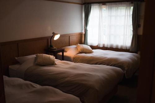 two beds in a hotel room with a window at Hakuba Pension & Log Hotel Meteor in Hakuba