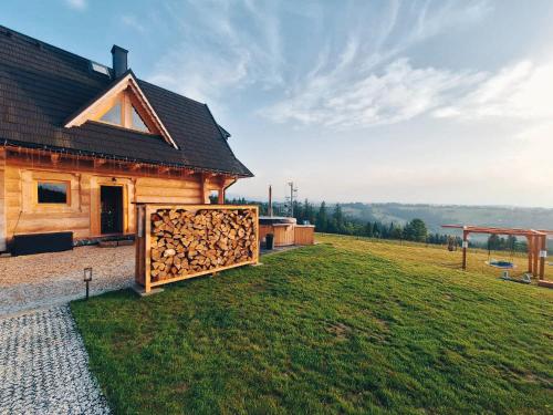 a house with a pile of fire wood in front of it at Legenda Lasu - drewniany domek w górach z jacuzzi, przy stoku narciarskim Kotelnica, Białka Tatrzańska, w pobliżu Term Bania in Groń