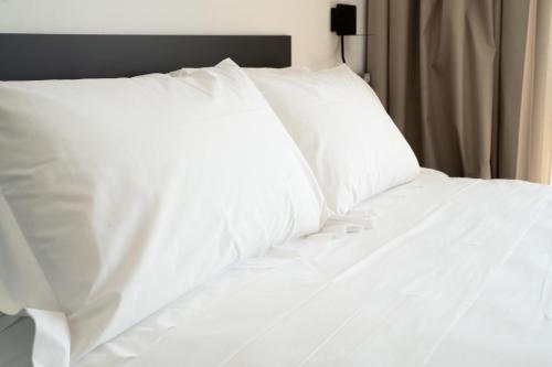 a white bed with white sheets and pillows at MòN Luxury Rooms SPA in Nicolosi