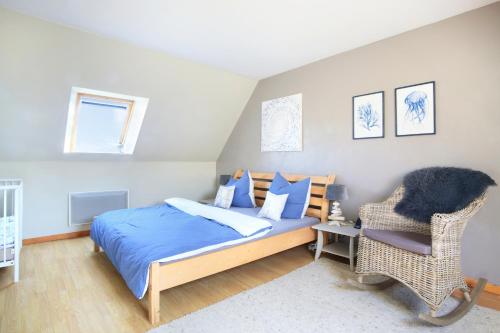 ein Schlafzimmer mit einem Bett und einem Stuhl in der Unterkunft La Maison Merlin - Maison avec piscine Sénoville in Senoville