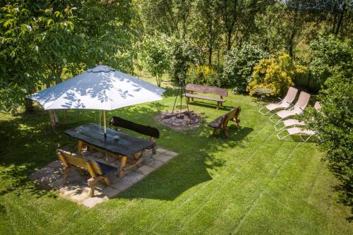 a picnic table with an umbrella and benches in the grass at Agroturystyka "Pograniczna" in Ober Wüstegiersdorf