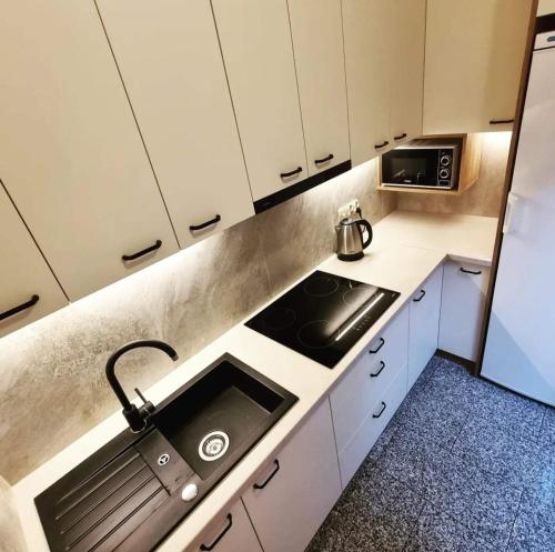 a kitchen with white cabinets and a sink and a microwave at Willa pod Smrekiem in Białka Tatrzanska