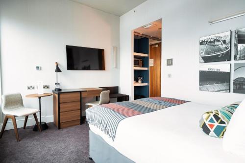 ein Schlafzimmer mit einem Bett, einem Schreibtisch und einem Fernseher in der Unterkunft Sandman Signature Newcastle Hotel in Newcastle upon Tyne