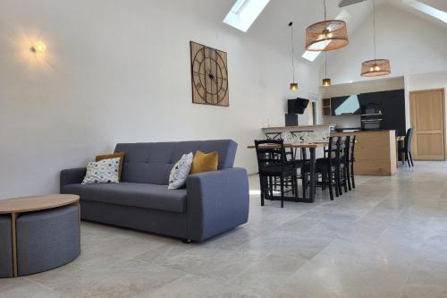 un salon avec un canapé bleu et une cuisine dans l'établissement Gîte Chemin de Camet entièrement rénové, 8 pers avec 4 chambres et spa Pordic, Côtes d'Armor, à Pordic