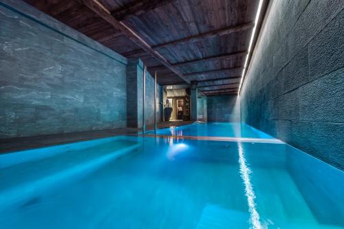 une piscine avec de l'eau bleue dans un immeuble dans l'établissement Chalet Orso - Val d'Isère - 13 pers - 520m2, à Val dʼIsère