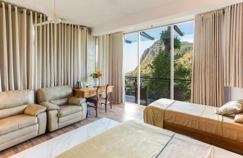 ein Hotelzimmer mit einem Bett, einem Schreibtisch und einer Couch in der Unterkunft Ravana Heights in Ella