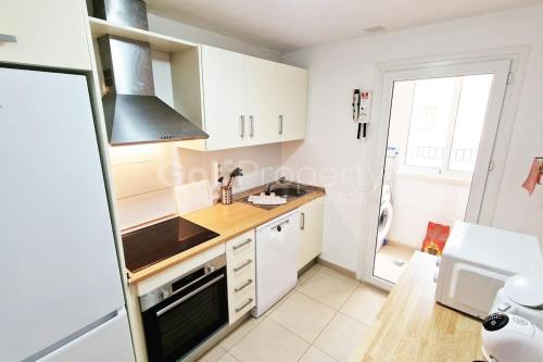 a kitchen with white cabinets and a stove top oven at Lovely Ground Floor 2 Bed with Golf Course Views in Sucina