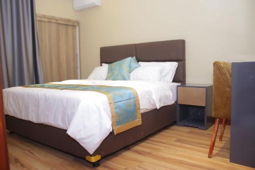 a bedroom with a large bed with white sheets and blue pillows at Taj mahal residencial in Maputo