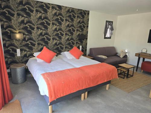 a bedroom with a bed with red pillows and a couch at Les Loges du Luberon in Coustellet