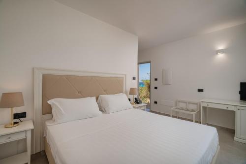 a bedroom with a large white bed and a desk at Bellevue Sardinia Resort Affiliated by Meliá in Valledoria