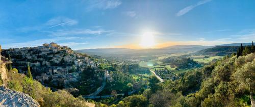 a view of a town on a hill with the sun setting at La Suite Gordes in Gordes