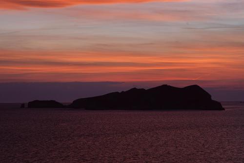 a sunset over a group of mountains in the ocean at 7Pines Resort Ibiza, part of Destination by Hyatt in San Jose