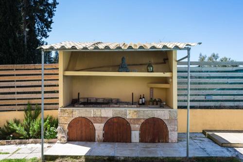 a patio with an outdoor kitchen with two wooden doors at Villa Anastasia with Private Pool & Outdoor Spa Tub in Agios Ioannis