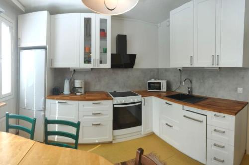 a kitchen with white cabinets and a table with chairs at Tyylikkäästi Retroa ja modernia Tampere Hervanta Atomikatu 5 in Tampere