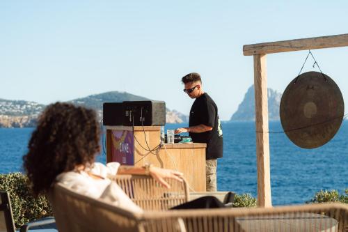 a man standing at a bar in front of the water at 7Pines Resort Ibiza, part of Destination by Hyatt in San Jose