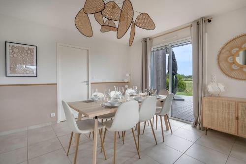une salle à manger avec une table en bois et des chaises blanches dans l'établissement À 650m du bord de mer, belle maison neuve pour 8, à Piriac-sur-Mer