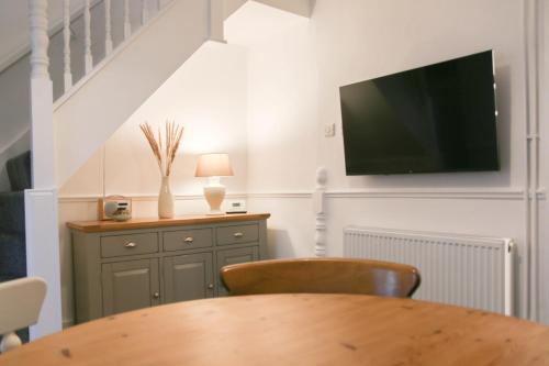 a dining room with a table and a television on the wall at Newly Refurbished 2-Bed with Patio, Netflix & Wi-Fi in Worksop