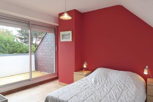 - une chambre dotée d'un mur rouge avec un lit et une fenêtre dans l'établissement REF 015 Golfe du Morbihan - Kerners -Maison mitoyenne 3 couchages, à Arzon