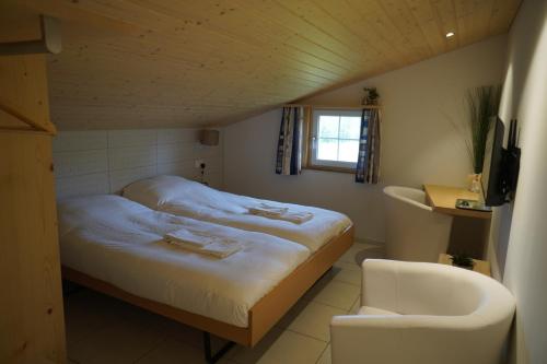 a small bedroom with a bed and a chair at Hotel Kaubad in Appenzell